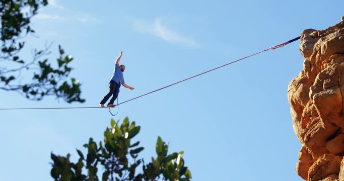 Highline athlete balancing on slackline in rocky mountain 