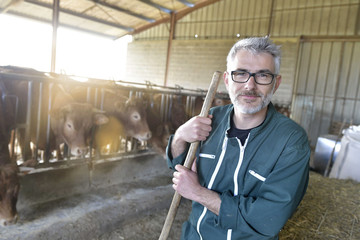 Smiling farmer standing in cow shed