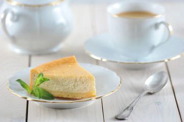 cheesecake and a mint leaf on the saucer with a Golden rim