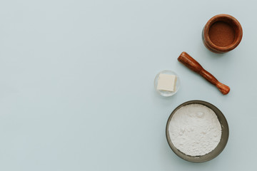 Flat lay with flour, butter and cocoa powder on pastel background. Baking concept