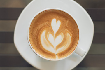A Cup of hot latte art coffee on wooden table