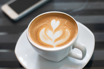 A Cup of hot latte art coffee on wooden table