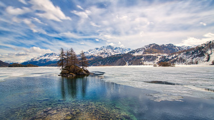 Engadine Valley. Spring thaw with islet on the lake - obrazy, fototapety, plakaty