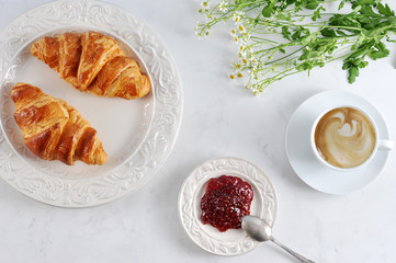 Breakfast with croissants, raspberry jam and cappuccino