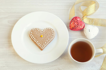 Love consept.  Valentines day. Gingerbread in the shape of heart, a cup of tea, decorative hearts on a wooden table 