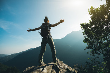 successful hiker with arms outstretched on sunrise mountain top