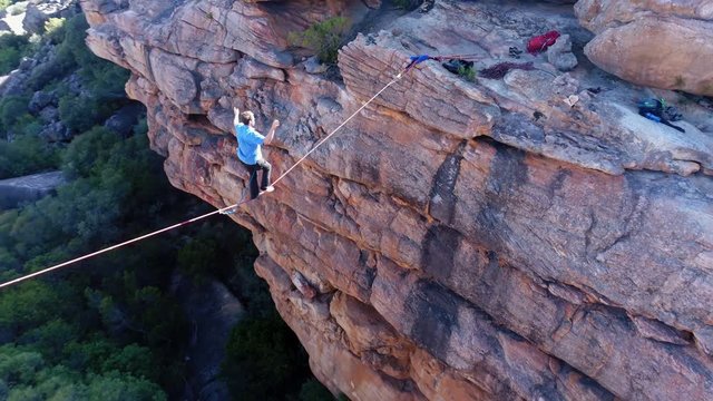 Male highliner walkng on a rope over rocky mountains