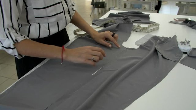 Training of tailoring of trousers. Female hands are painted with a tailor's crayon on a gray cloth
