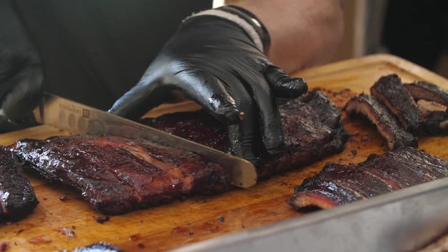 Close-up of a professional cutting BBQ ribs for serving.