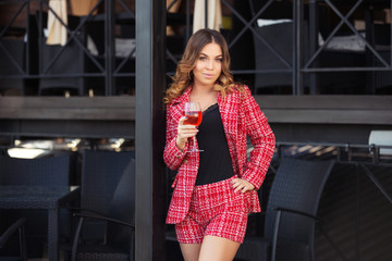 Young fashion woman in red tweed jacket and shorts suit at sidewalk cafe