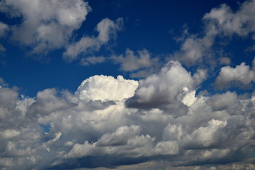 Fototapeta na wymiar In the blue sky a cumulus cloud. The sun is shining. A pleasant calm wind. Black key. 
