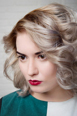 Naklejka premium Portrait of a stylish blonde girl with a professional make-up and hairdress on a light background close-up.