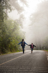 Fototapeta na wymiar A little girl and mother run on a road in the forest