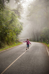 A little girl run on a road in the forest
