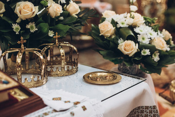 golden crowns and bible and wedding ring on altar in church at wedding matrimony. traditional religious wedding ceremony