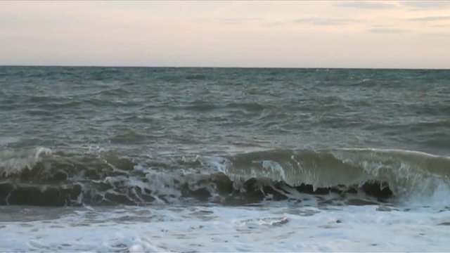 UK July 2012 - slow motion footage of waves crashing on a pebble beach at sunset.