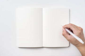 Design concept - Top view of notebook blank page and man's hand holding ballpoint pen isolated on white background for mockup