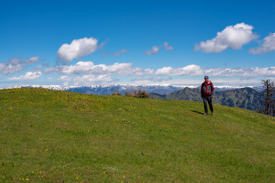 Adventurer is walking along green mountain meadow