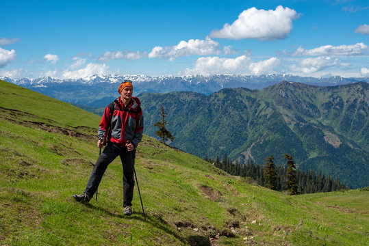 Adventurer stands on a green mountain meadow