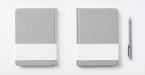 Design concept - Top view of hardcover gray linen notebook and ballpoint pen isolated on white...