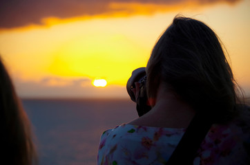 Woman takes photo with camera of sunset or sunrise from cruiseship cruise ship liner
