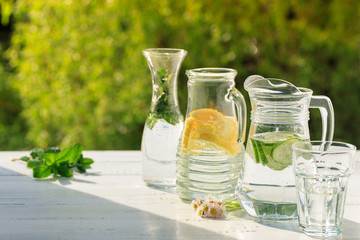 Three variants of fresh homemade lemonade with lemon, cucumber and mint. Lemonade in jugs and...