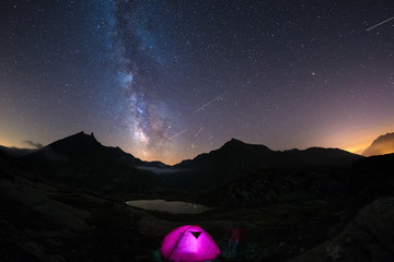 Camping under starry sky and milky way at high altitude on the Alps. Illuminated tent in the...