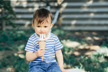 a child in a t-shirt on a bench eating ice cream in the summer, very hot and tasty