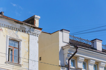 Fototapeta na wymiar part of an old building with crumbling plaster, broken wooden window, blue sky