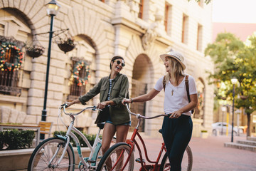 Friends walking with bicycles on street