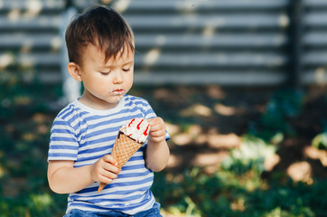 a child in a t-shirt on a bench eating ice cream in the summer, very hot and tasty