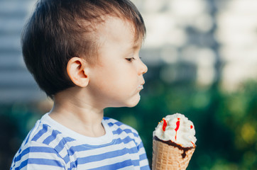a child in a t-shirt on a bench eating ice cream in the summer, very hot and tasty