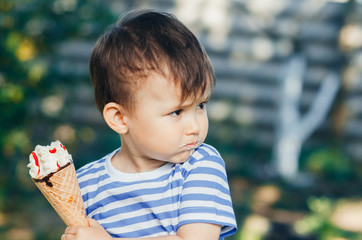 a child in a t-shirt on a bench eating ice cream in the summer, very hot and tasty