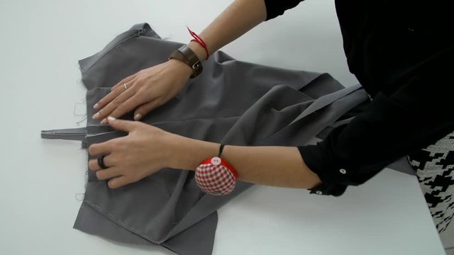 Training sewing trousers. Female hands smoothen gray cloth