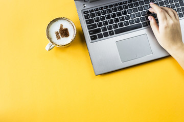 A cup of cappuccino on which is drawn a smile like a thumb up. Next to the laptop. Communication in social networks on the Internet concept