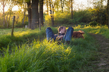 Fototapeta premium Happy teenage man having fun with dog in countryside during spring.