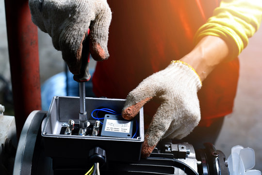 Electricians working on industrial panels, installing and assembling new wires.