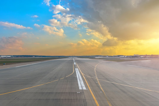 Runway At The Airport In The Sunset Sun Light Sky Blue Gradient Yellow Color Cumulus Clouds.