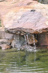 Der kleine Wasserfall: Wasser rinnt den Stein herunter ins Wasser