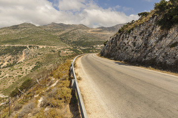 Perspective landscape of empty road between mountains, during sunny day on vacation in Greece. Roadtrip through valley up to the hill. 