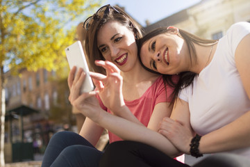 two girls enjoy the summer day and photographing with a mobile phone 
