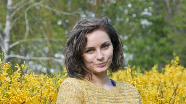 Beautiful green eyed young girl with short curly hair looks at camera and smiles flirting