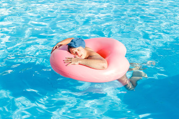 a drunk guy swims on inflatable circle in the pool. travel of a Russian tourist