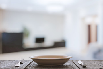 empty plate with fork and knife on wooden table