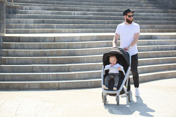 Father walking with a stroller and a baby in the city streets