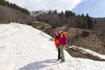 two standing hugging in the snow against the backdrop of mountains, a man and a woman in the mountains