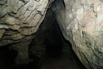 Beautiful cave. View from inside dark dungeon. Textured walls of cave. Background image of underground tunnel. Dampness inside cave. Light at end of tunnel.