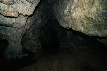 Beautiful cave. View from inside dark dungeon. Textured walls of cave. Background image of underground tunnel. Dampness inside cave. Light at end of tunnel.
