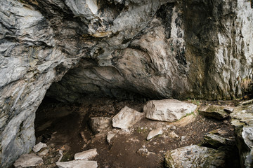 Beautiful cave. View from inside dark dungeon. Textured walls of cave. Background image of underground tunnel. Dampness inside cave. Light at end of tunnel.