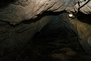 Beautiful cave. View from inside dark dungeon. Textured walls of cave. Background image of underground tunnel. Dampness inside cave. Lighting inside cave for excursions.